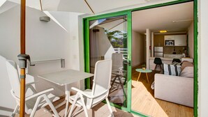 Een modern interieur met een eethoek, een bank en een keuken, zichtbaar door een open deur.