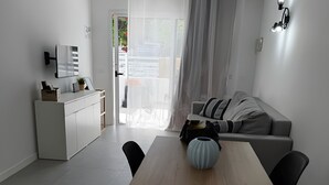 Een moderne, minimalistische woonruimte met een eethoek, een bank en een keuken.