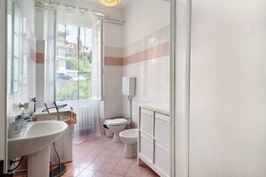 Casa de banho com lavatório, sanita e zona de duche.