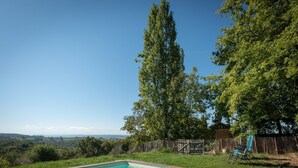 A swimming pool with a view of a forest and distant hills. - La Toumet – Family Home with Pool and Pyrenees View (MALABAT)