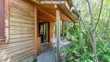 Een houten hut met een veranda, buiten zitplaatsen en een deur naar de binnenruimte.