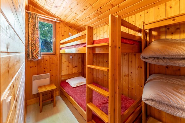 Una cabaña con literas, una mesita y un ventanal con cortinas.