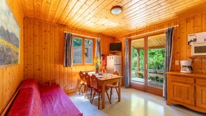 Una cabaña de madera con comedor, cama y cocina.