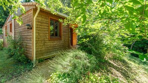 A wooden cabin with a window, surrounded by dense greenery. - Chalet 'Gite Lavande' with Shared Pool, Private Terrace and Wi-Fi (Mirabel-aux-Baronnies)