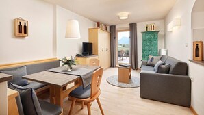 A modern hotel room with a dining area, a sofa, a TV, and a view of the outdoors. - Apartment 'Stöckerhof  Traube' with Mountain View, Shared Pool and Wi-Fi (Merano)
