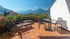 A terrace with a view of mountains, a table with chairs, and a small garden area. - Apartment 'Stöckerhof  Traube' with Mountain View, Shared Pool and Wi-Fi (Merano)