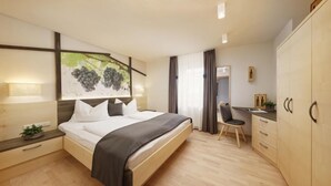 A modern hotel room with a bed, bedside table, chair, desk, and wardrobe. - Apartment 'Stöckerhof  Traube' with Mountain View, Shared Pool and Wi-Fi (Merano)