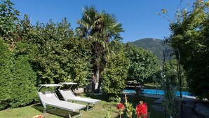 A poolside area with lounge chairs, a pool, and surrounding greenery. - Apartment 'Stöckerhof  Traube' with Mountain View, Shared Pool and Wi-Fi (Merano)