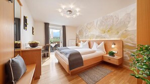 Un dormitorio moderno con cama, mesitas de noche, un banco, un mural floral grande y vistas al exterior.