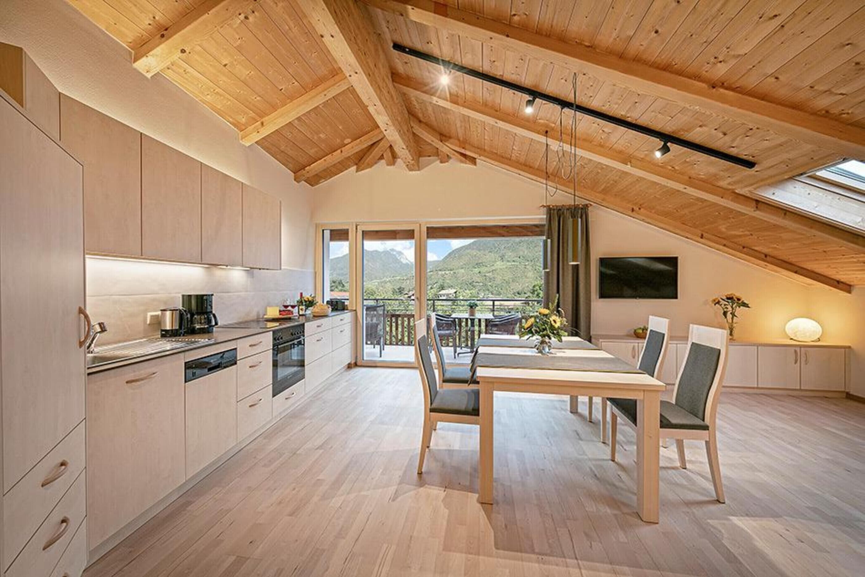 Eine moderne Küche mit Holzschränken und einem Essbereich mit Tisch und Stühlen.