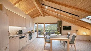 A modern kitchen with wooden cabinets and a dining area with a table and chairs. - Apartment 'Stöckerhof  Sonne' with Mountain View, Shared Pool and Wi-Fi (Merano)