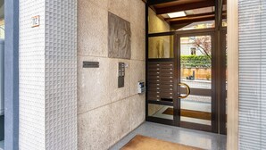 Een gevel met een structuur, een deur met een metalen handgreep en een deurmat.