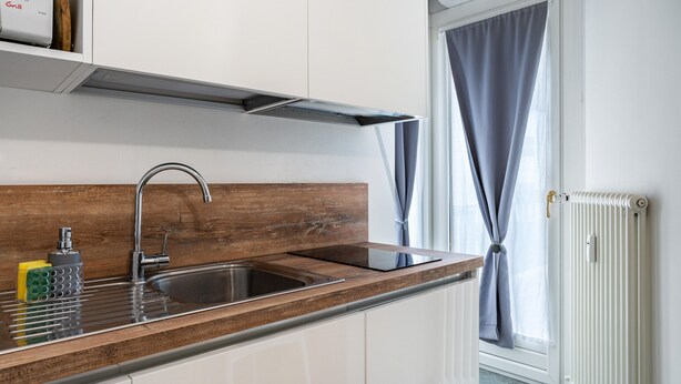 Een moderne keuken met een RVS spoelbak, een houten aanrecht en een inbouw afzuigkap.
