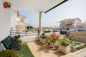 A balcony with a green bench, potted plants, and a small garden area. - Holiday Home 'Casa Da Cândida' with Mountain View, Private Terrace and Wi-Fi (Nazaré)