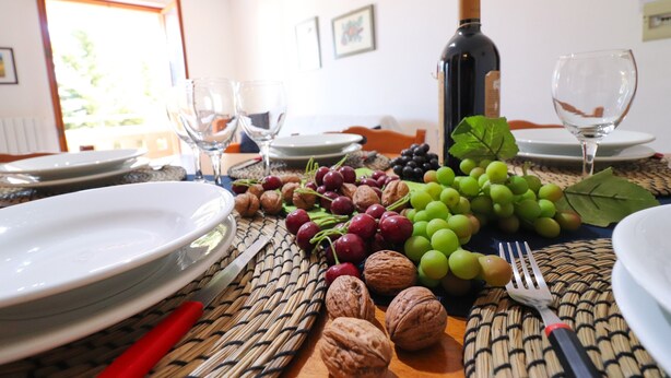 Une table à manger dressée avec des assiettes, des verres à vin, une bouteille de vin et un assortiment de fruits et de noix.