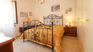 Un dormitorio con una cama, una mesita de noche, una lámpara, un candelabro y una puerta.
