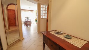 Un pasillo con una mesa de madera, un mantel de encaje y una puerta que da a un comedor.
