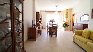 Un salón espacioso con comedor, un sofá amarillo y un gran aparador de madera con puertas de cristal.