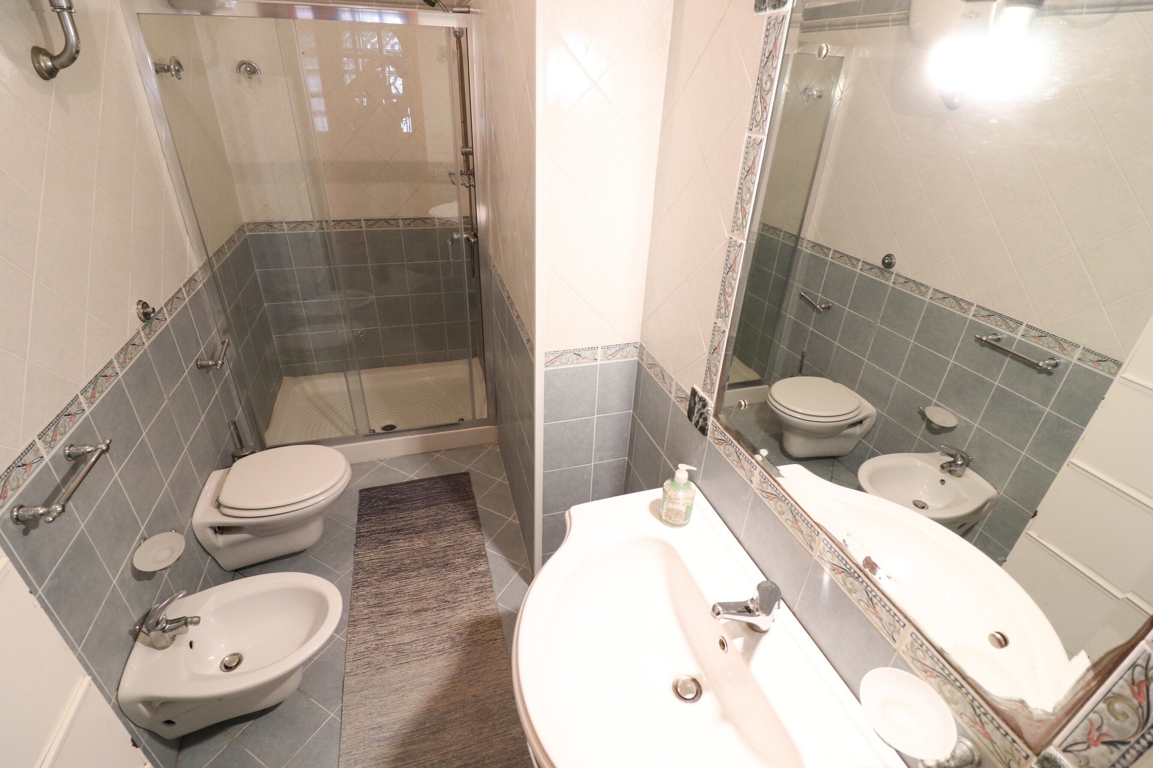 Une salle de bain équipée d’une douche, de toilettes, d’un bidet et d’un lavabo.