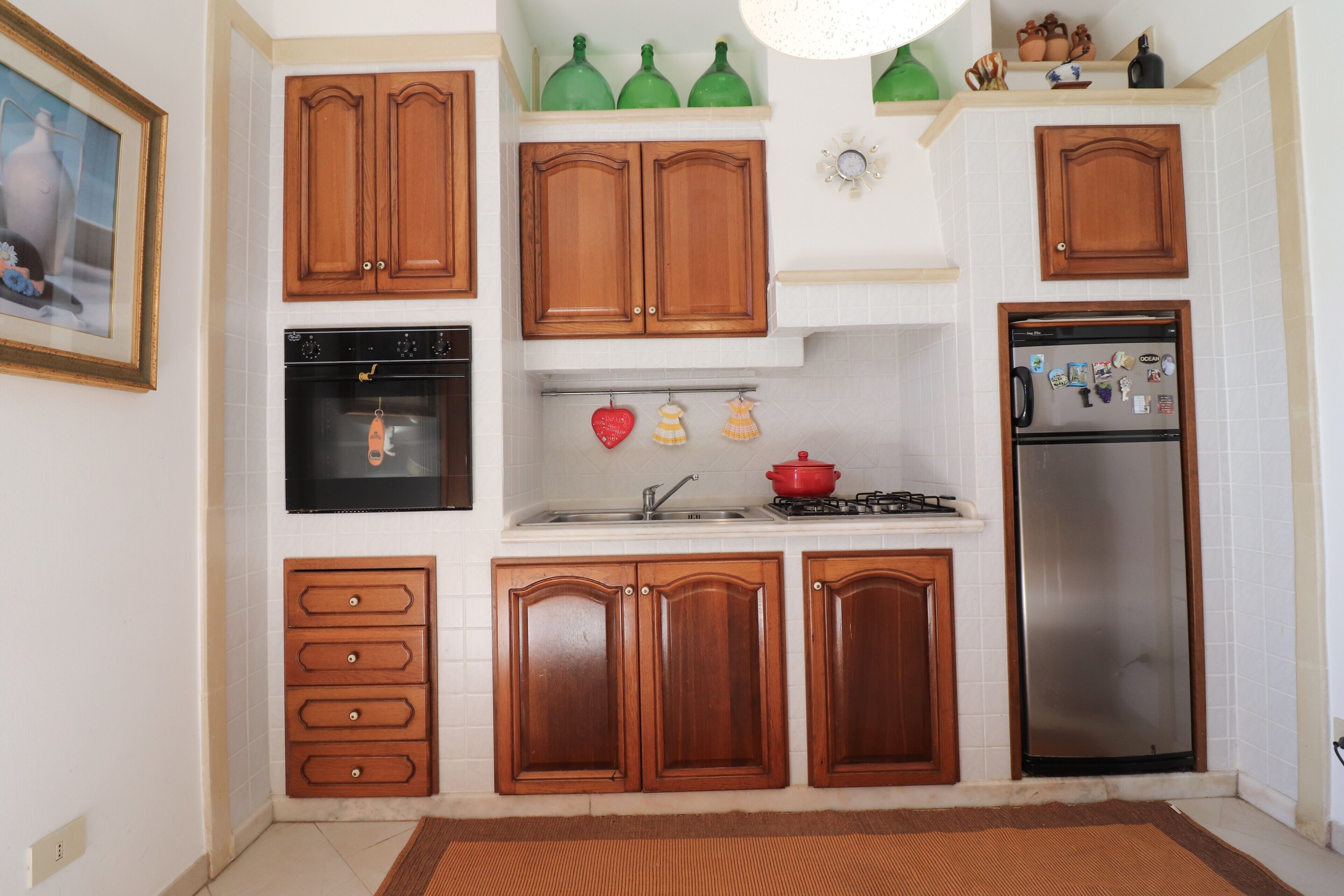Une cuisine avec des meubles de rangement en bois, une cuisinière, un four et un réfrigérateur.