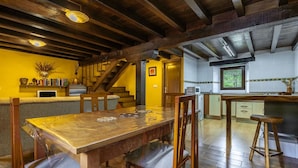 Ein Essbereich mit Holztisch und -stühlen, eine Küche mit weißen Schränken und eine Treppe, die zu einer anderen Ebene führt.