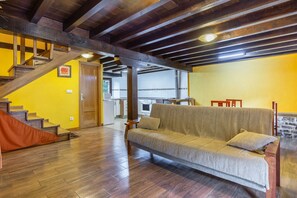 Una habitación con una escalera de madera, un sofá y una zona de cocina.