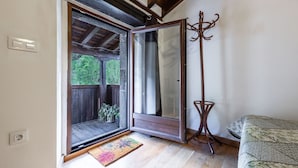 Eine geöffnete Schiebetür, die zu einem Balkon mit Holzboden und einem Blumentopf führt.