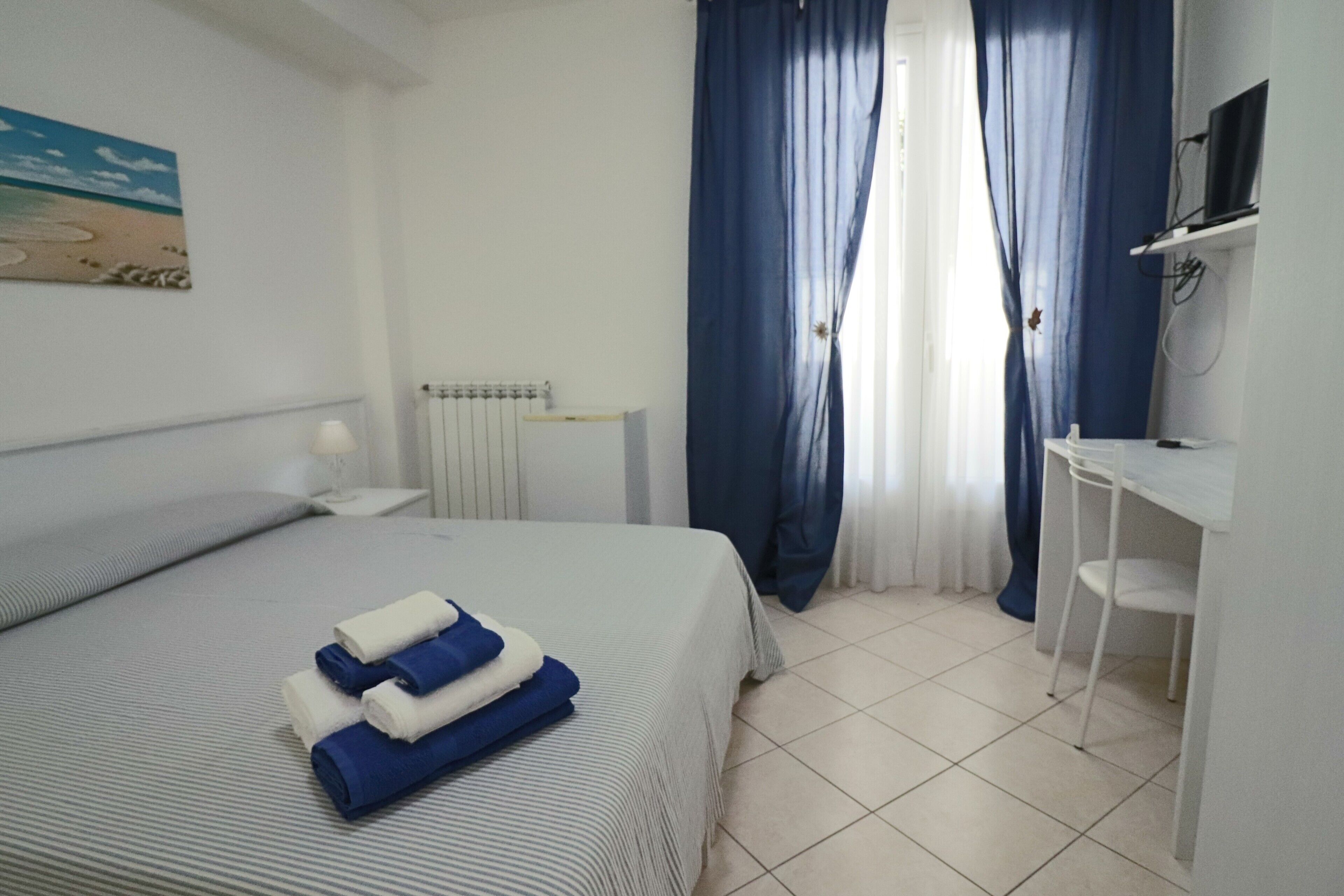 Een hotelkamer met een bed, een bureau, een stoel, een televisie en een schilderij aan de muur.