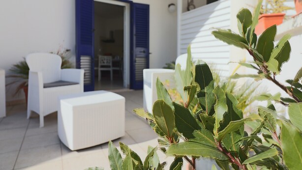 A modern outdoor seating area with white furniture and a blue door.