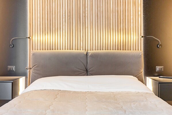 Un lit avec une tête de lit, des tables de chevet et un mur avec des stores verticaux.