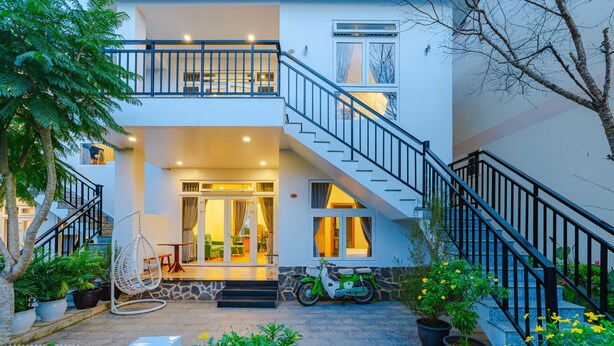 Une maison à deux étages avec un balcon, un escalier et un fauteuil suspendu.