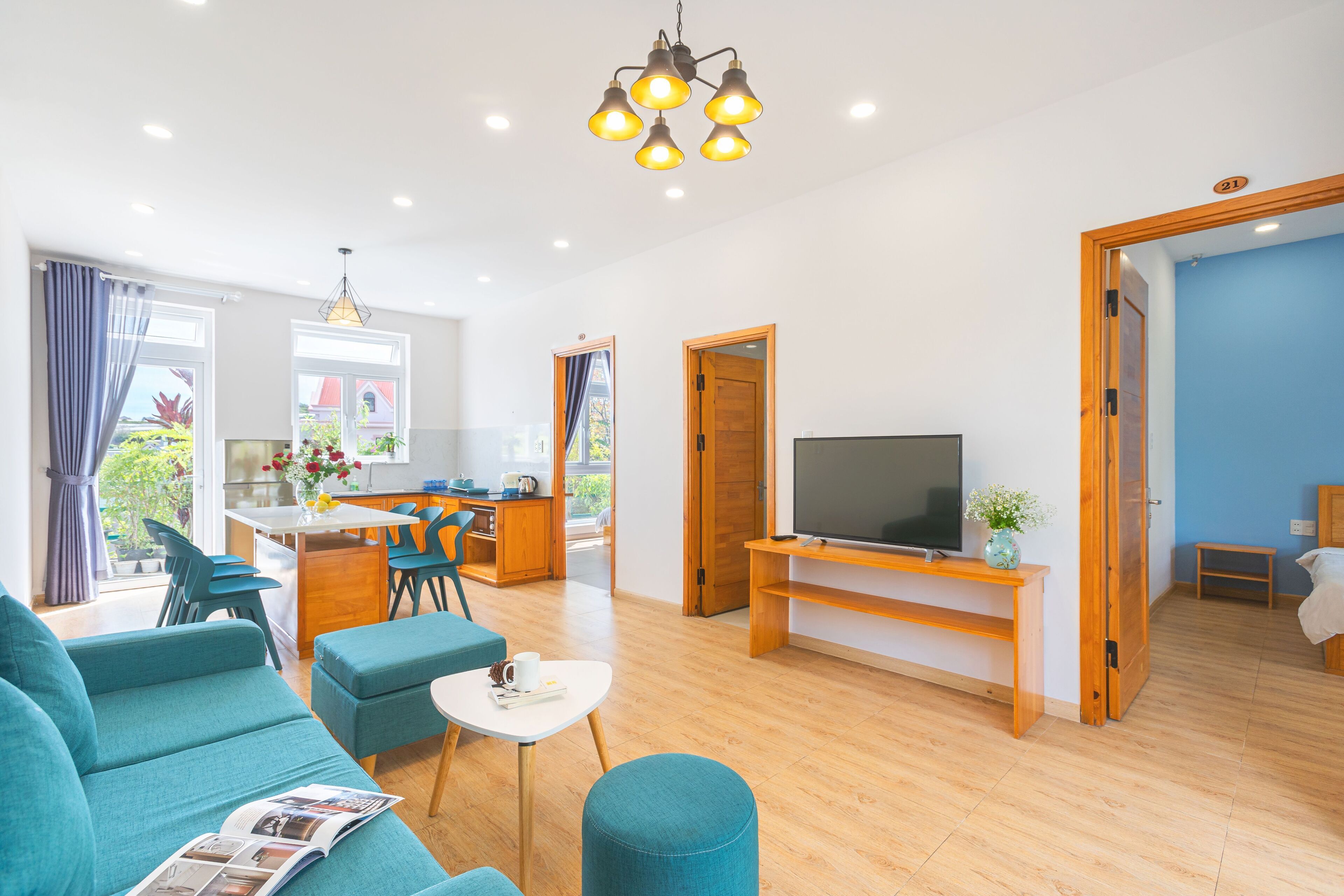 Una sala moderna con un sofá, una mesa de centro y un televisor. Hay un comedor con sillas y una mesa, y una cocina al fondo.