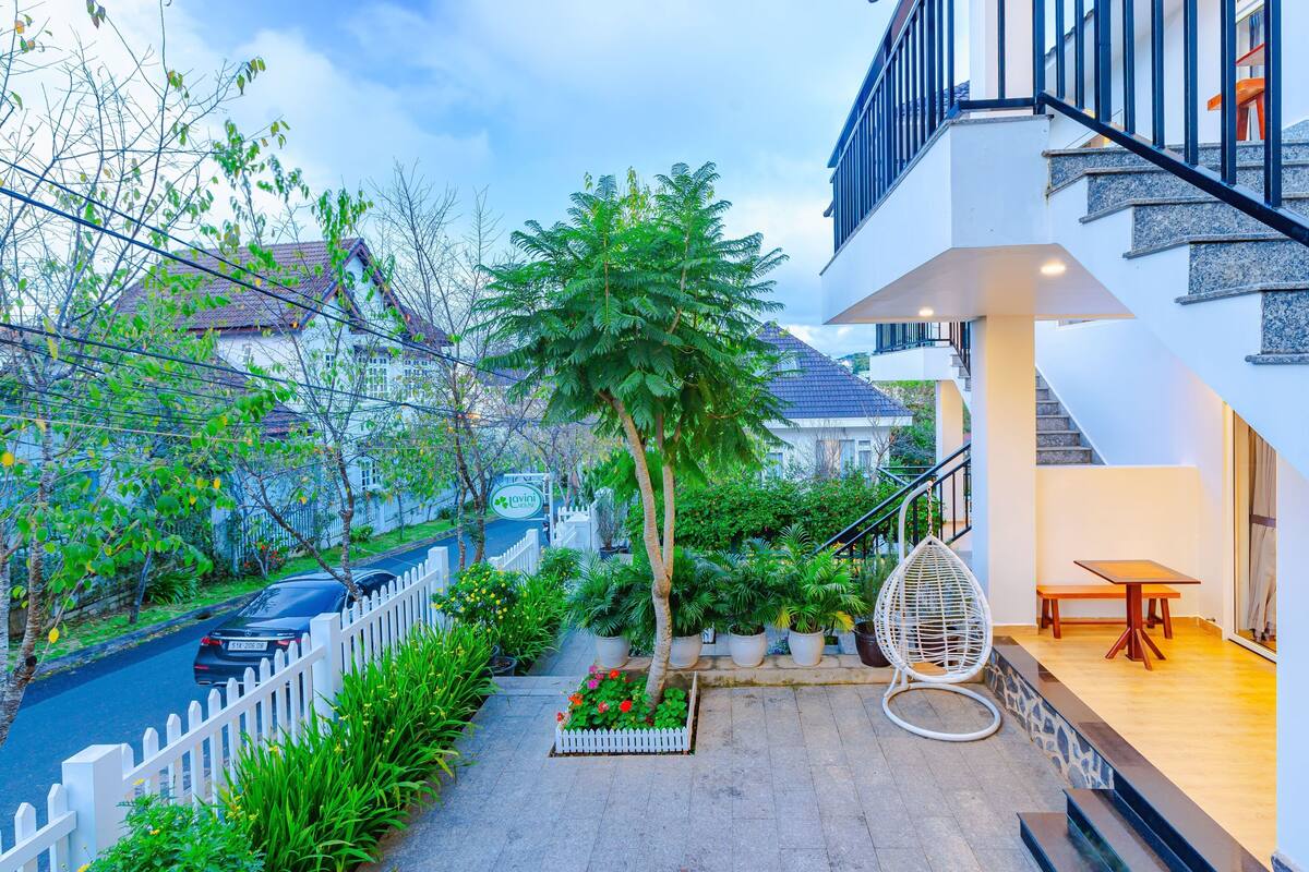A modern building with a white exterior, a staircase, and a balcony with a wicker chair.