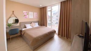 Une chambre d’hôtel moderne, dotée d’un grand lit, d’un bureau avec une chaise, d’une télévision et d’une fenêtre avec des rideaux.