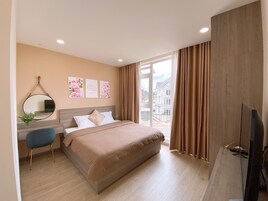 Una habitación de hotel moderna con una cama grande, un escritorio con una silla, un televisor y una ventana con cortinas.