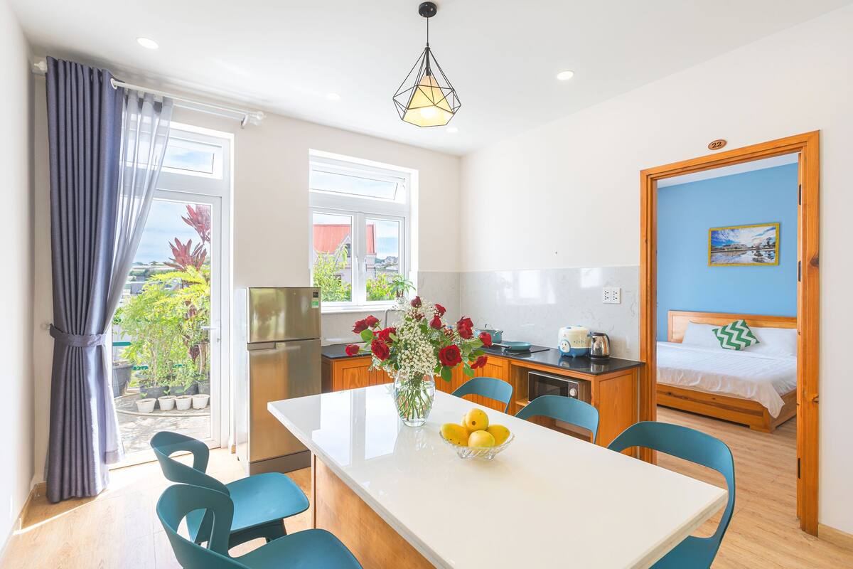 A modern kitchen with a dining area, a bed, and a view of the outdoors.