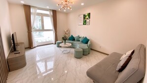 Un salon moderne avec un canapé gris, un canapé bleu clair, une table basse et un téléviseur posé sur un meuble en bois.