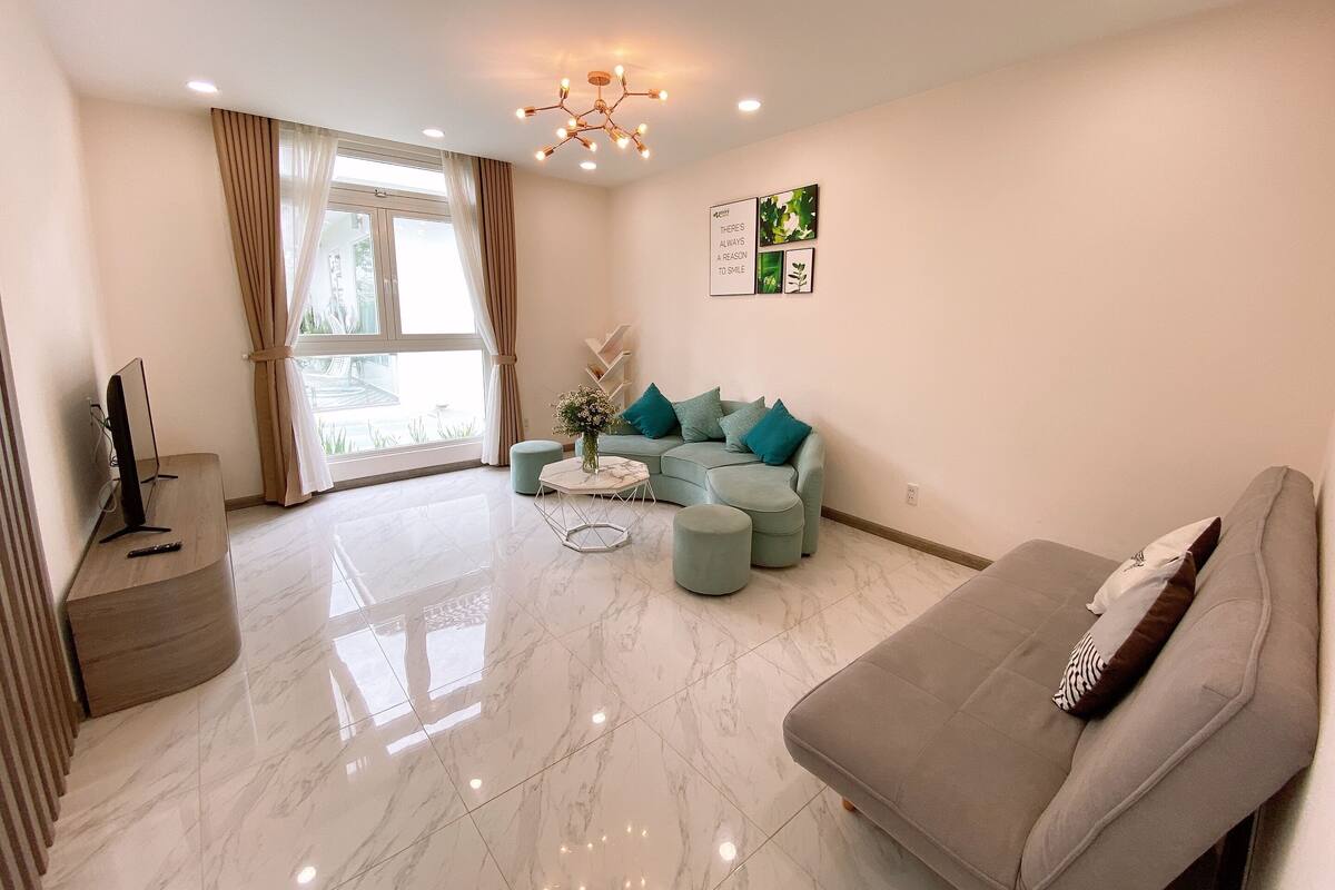 A modern living room with a grey sofa, a light blue sofa, a coffee table, and a TV on a wooden stand.