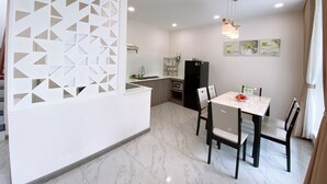 Une cuisine moderne avec un îlot central blanc, un réfrigérateur noir et un coin repas comprenant des chaises et une table.