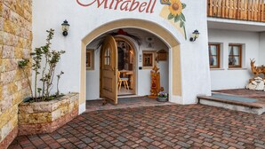 Un immeuble avec une enseigne indiquant « Appartements Mirabell », une entrée dotée d’une porte en bois et une cour pavée de briques.
