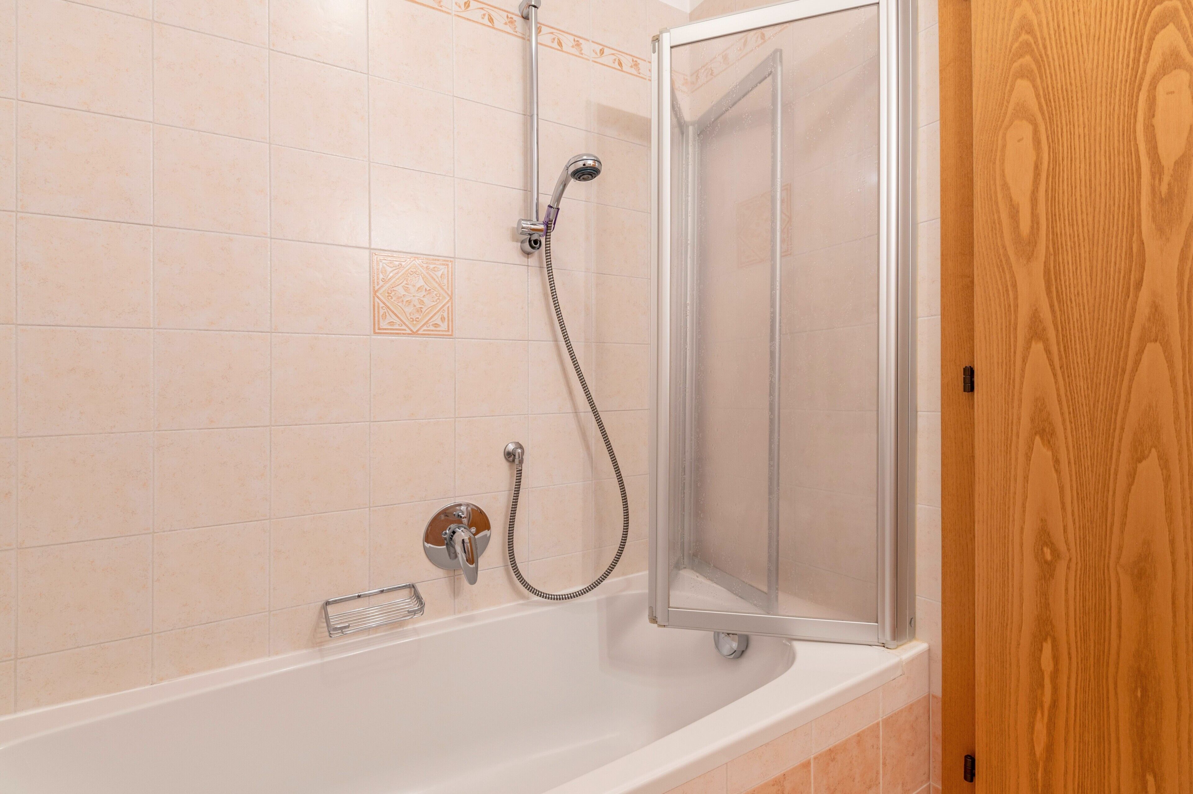 Ein Badezimmer mit Duschkabine, Badewanne und Holztür.