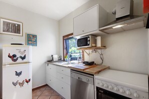Cozinha equipada com micro-ondas, fogão, máquina de lavar louça e frigorífico.
