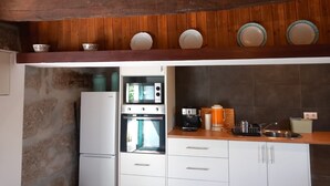 A kitchen with wooden beams, a refrigerator, oven, and a coffee maker.