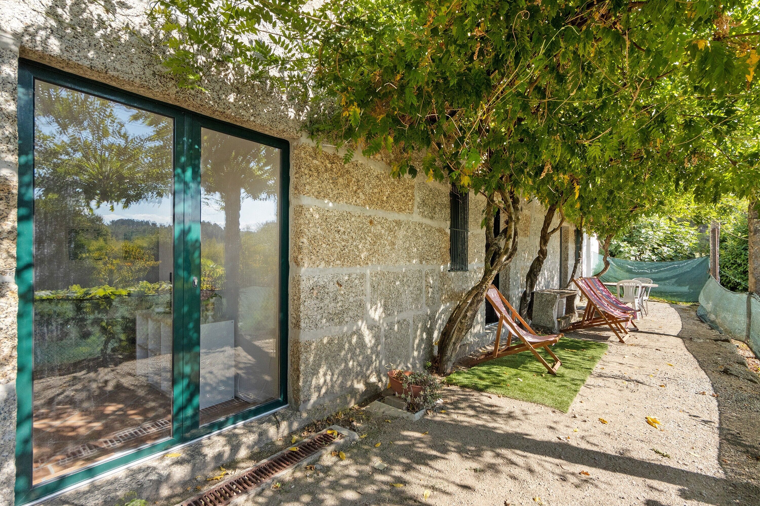 A stone building with large windows, a tree-lined patio, and outdoor seating.