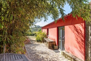 A red building with a stone-paved entrance, a bench, and a door.
