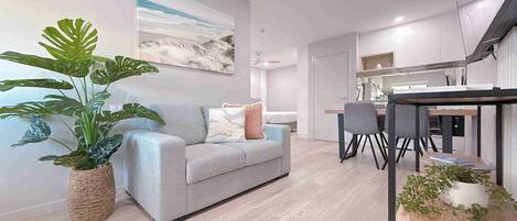 Una sala de estar moderna con un sofá gris, una planta grande en maceta y un comedor con una mesa y sillas.