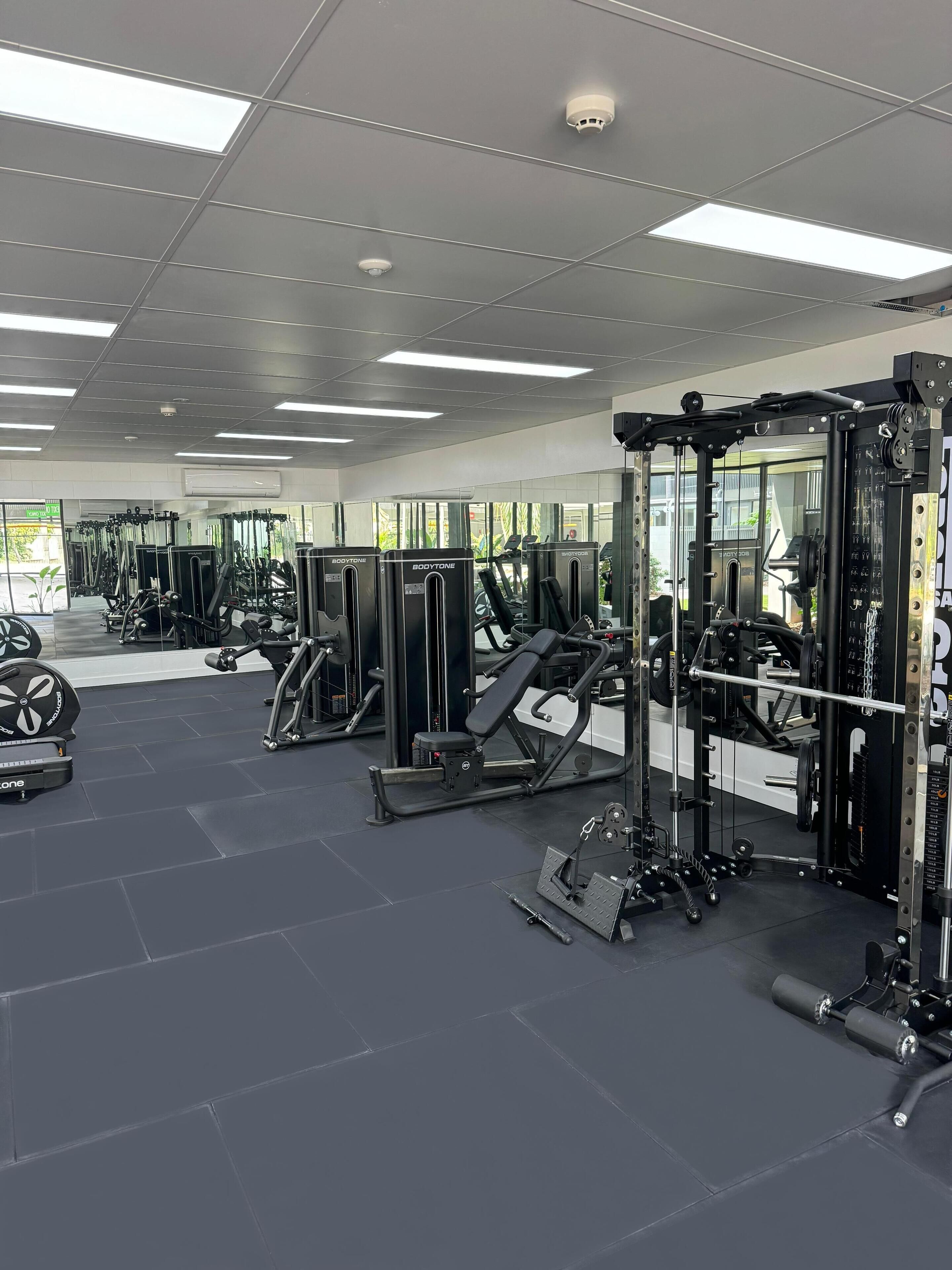 Un gimnasio con diversos equipos de ejercicio, como cintas de correr, máquinas de pesas y pesas libres.