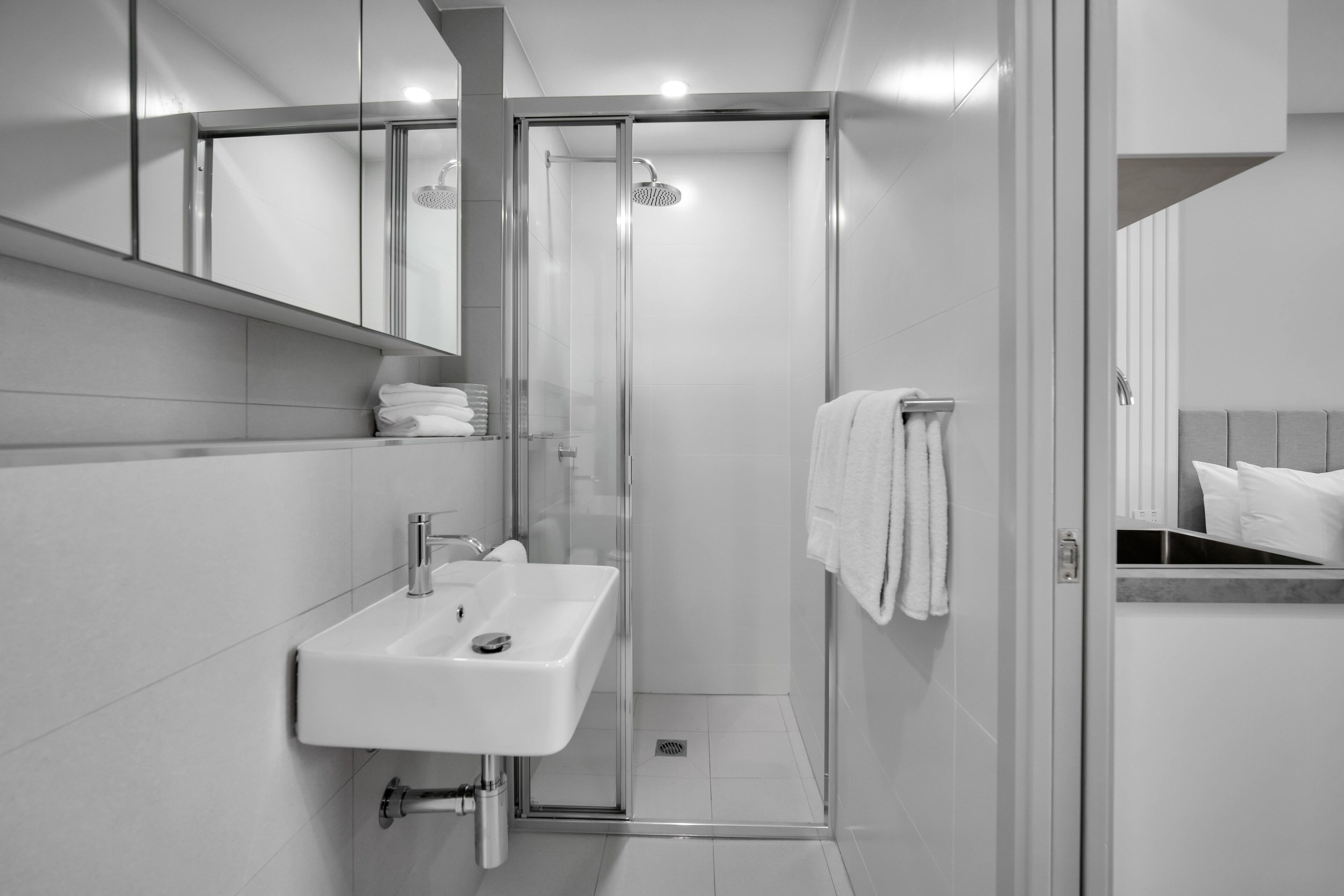 Un bagno moderno con doccia vetrata, lavandino bianco e porta asciugamani.