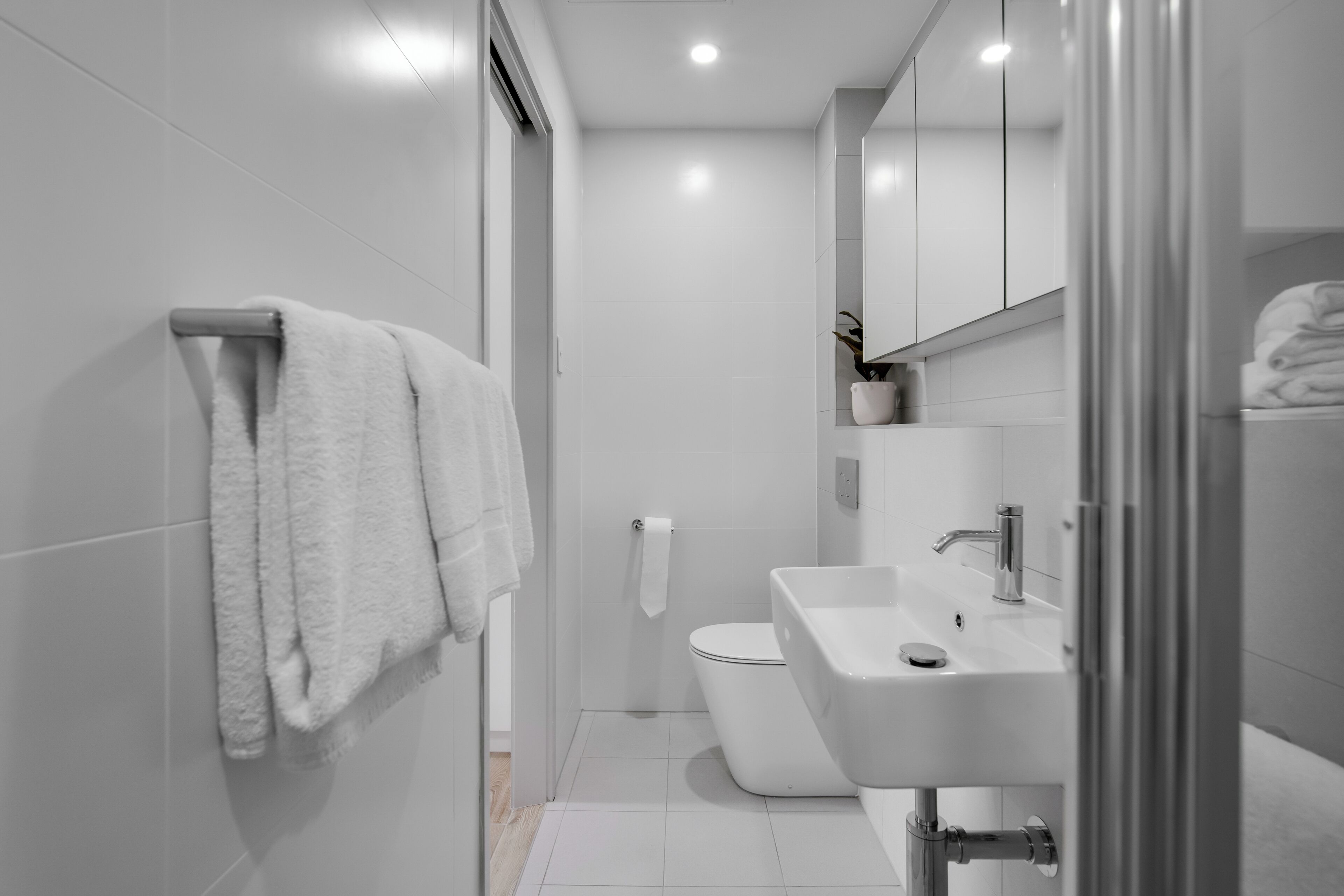 Uma casa de banho moderna com sanita, lavatório e suporte para toalhas.