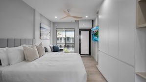 Une chambre moderne avec un grand lit, un ventilateur de plafond et un balcon avec vue.